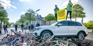 tivisten von Greenpeace demonstrieren vor dem Reichstag mit einer Aktion, bei der ein Auto über Fahrräder fährt.