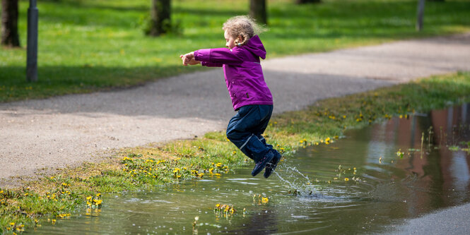 Ein Mädchen springt in eine Pfütze