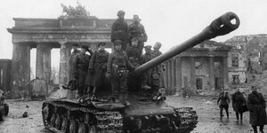 Soldaten der Roten Armee besteigen im Mai 1945 am Brandenburger Tor einen sowjetischen Panzer