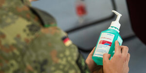 Ein Soldat hält eine Flasche mit Desinfektionsmittel