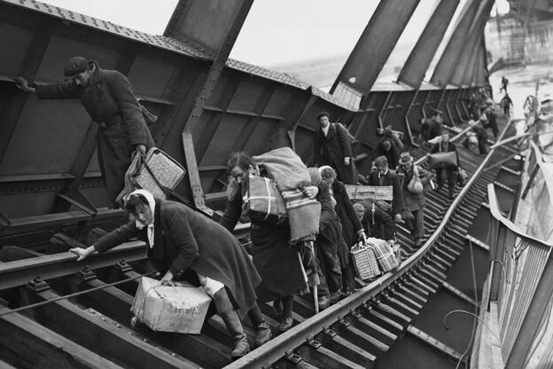 Menschen mit Gepäck klettern über eine zerstörte Brücke