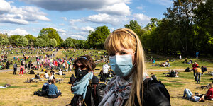 Zwei Frauen mit Maske in einem Park.