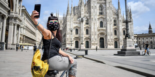 Eine Frau mit Mundschutz macht ein Selfie mit ihrem Handy