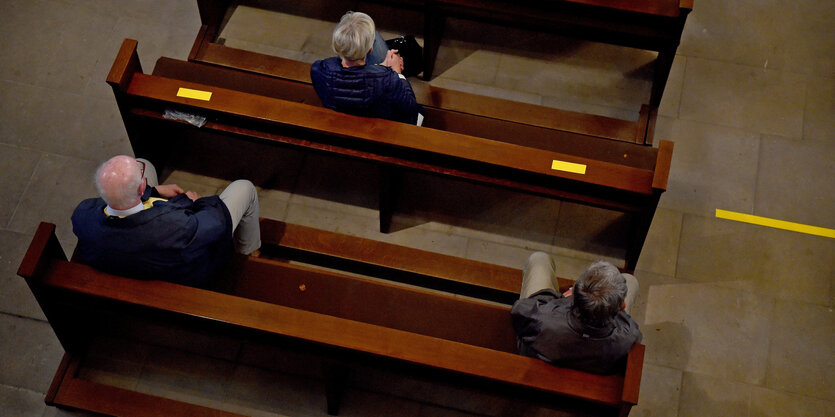 Gottesdienstbesucher sitzen während des Gottesdienstes in der St. Peter Kirche auf Kirchenbänken, auf denen gelbe Klebestreifen zur Einhaltung der Abstandsregelungen zum Schutz vor dem Coronavirus angebracht wurden.