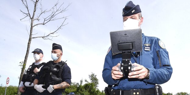 Polizisten mit Mundschutz und technischem Gerät
