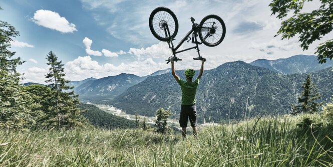 Mann hebt ein Fahrrad hoch auf einer Wiese