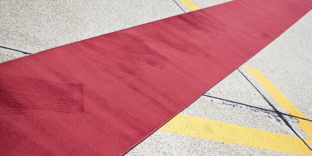 Ein leerer roter Teppich auf einem Flughafen-Feld