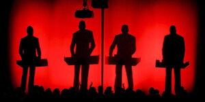 Die Schatten der Band Kraftwerk bei einem Auftritt in der Schweiz vor rotem Hintergrund