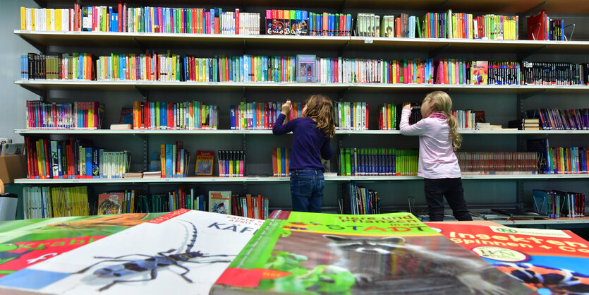 Kinder stehen vor einem Bücherregal in einer Bibliothek