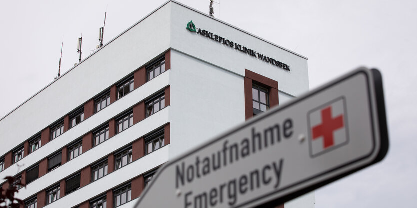 Hochhaus von unten, davor Wegweiser "Notaufnahme" mit rotem Kreuz