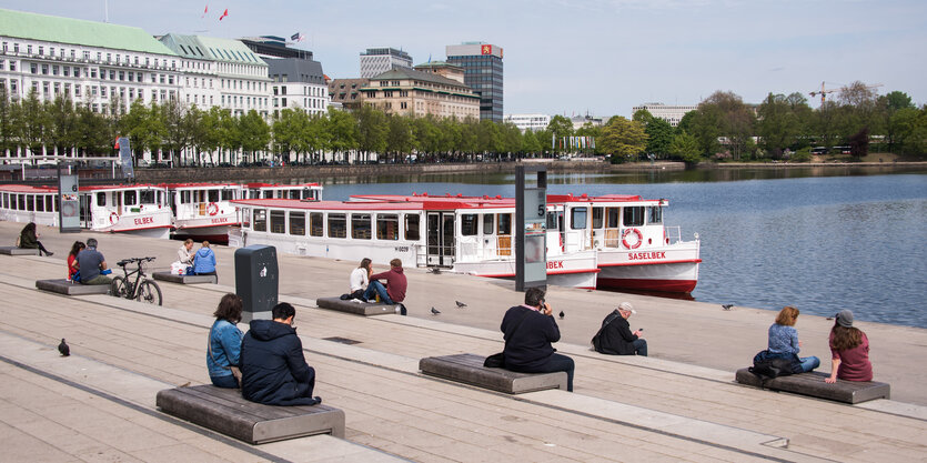 Menschen sitzen in großem Abstand auf den Treppen an der Binnenalster