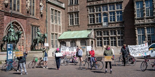 Menschen demonstrieren mit Abstand und Transparenten vor dem Bremer Rathaus