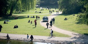 Ein Polizeiwagen zwischen Spaziergängern in einem Park