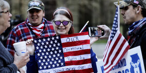 eine Demonstrantin mit einer US-Flagge auf die sie ihre Forderungen geschrieben hat
