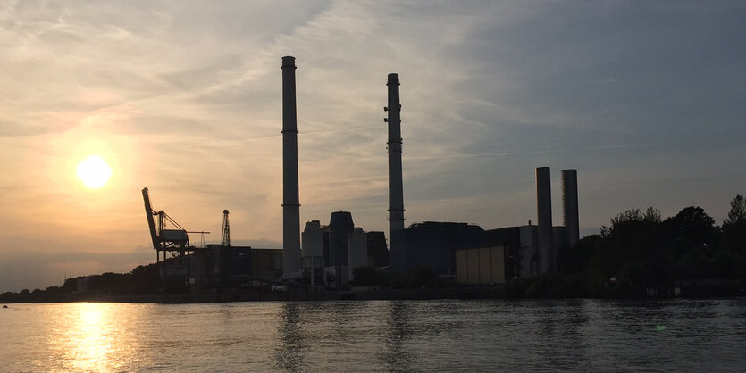 Silhouette vor Abendhimmel mit Kran und mehreren Schornsteinen