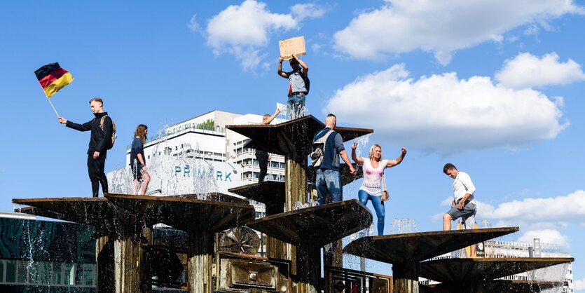 Personen mit Deutschlandfahnen sind auf einem Brunnen