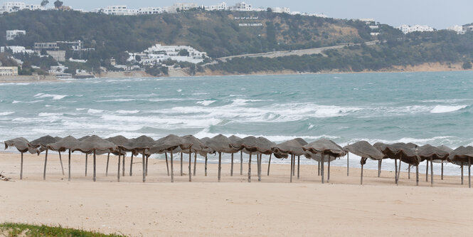 Unbenutzte Sonnenschirme an einem leeren Strand