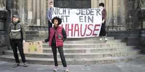 Demonstrierende stehen Mitte April auf den Treppen des Bremer Doms und halten Transparente:Sie fordern die Schließung der Sammelunterkunft Lindenstraße und erinnern daran, dass nicht jede*r ein zu Hause hat.
