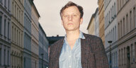 Der Schauspieler Robert Stadlober posiert vor einer Häuserschlucht
