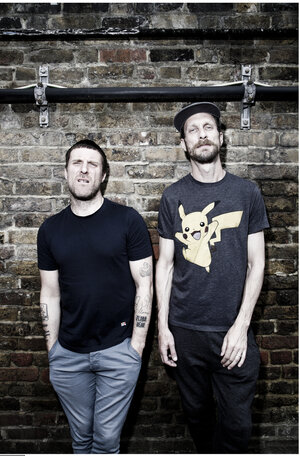 Jason Williamson und Andrew Fearn lehnen an einer Backsteinmauer Jason Williamson und Andrew Fearn lehnen an einer Backsteinmauer