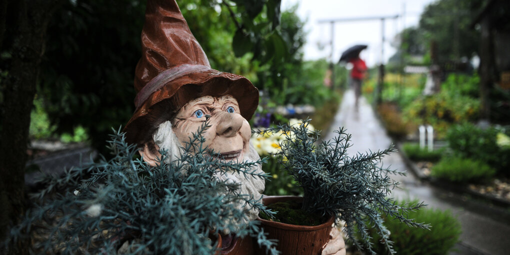 Ein Gartenzwerg steht in einer Kleingartenanalage