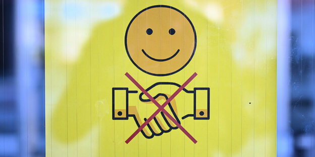 Ein Schild zeigt ein freundlich lächelndes Gesicht und zwei durchgestrichen Hände, die zum Gruß gereicht werden