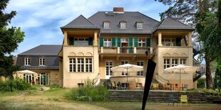 Gartenseite einer Villa mit Terrasse und Wiese davor