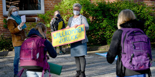 Lehrer halten ein Schild mit der Aufschrift Willkommen hoch