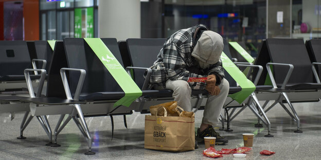 Ein obdachloser Mann sitzt in Frankfurt am Flughafen