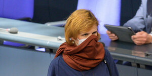 Katja Kipping im Bundstag. Sie trägt eine medizinische Schutzmaske und darüber noch ihren Schal als zusätzlichen Mundschutz