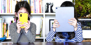 Zwei Kinder spielen an ihrem Smartphone und Tablet