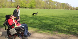 Frau im Rollstuhl mit ihrer Assistentin im Park