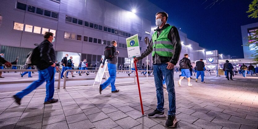 Ein sogenannter Werkslotse vor dem BMW-Werk Dingolfing. Er soll Mitarbeitendedabei unterstützen, Corona-Verhaltensregeln einzuhalten