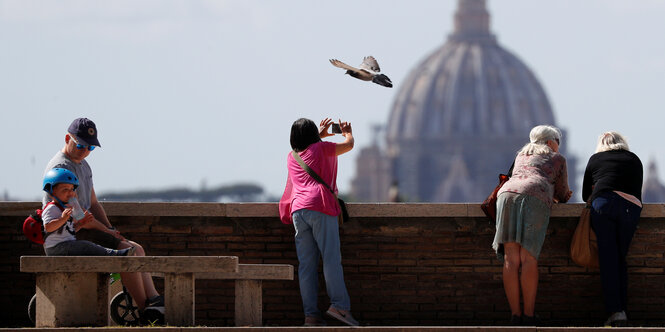 Menschen in einem Park in Rom, im Hintergrund der St. Petersdom