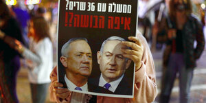 Eine Demonstrantin hält ein Plakat mit den Gesichtern von Benjamin Netanjahu und Benny Gantz.