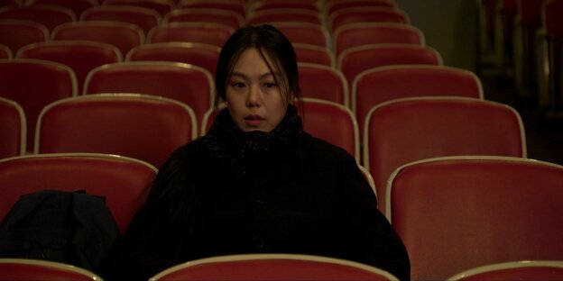 Eine Frau sitzt allein in einem Kinosaal (Szene aus dem Film "On the Beach at Night Alone")