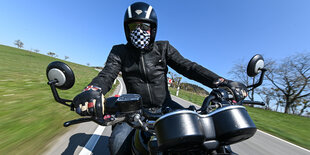 Blauer Himmel, ein Motorrad braust über eine Landstrasse