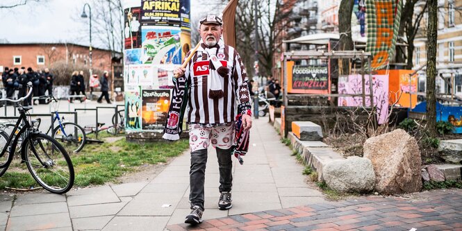 Ein Fan von Sankt Pauli läuft in Trikot und mit Fahne durch die Stadt