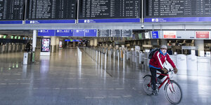 ein Mann fährt auf einem Fahrrad durch das menschenleere Terminal 1 am Frankfurter Flughafen