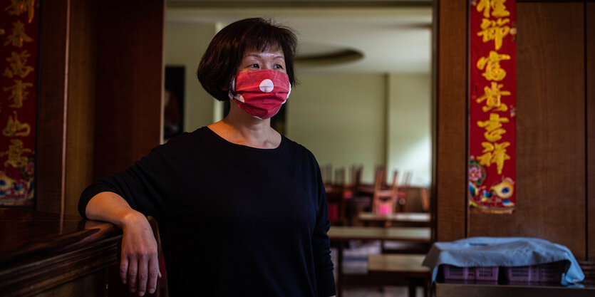 Eine Frau steht mit Maske in einem Restaurant