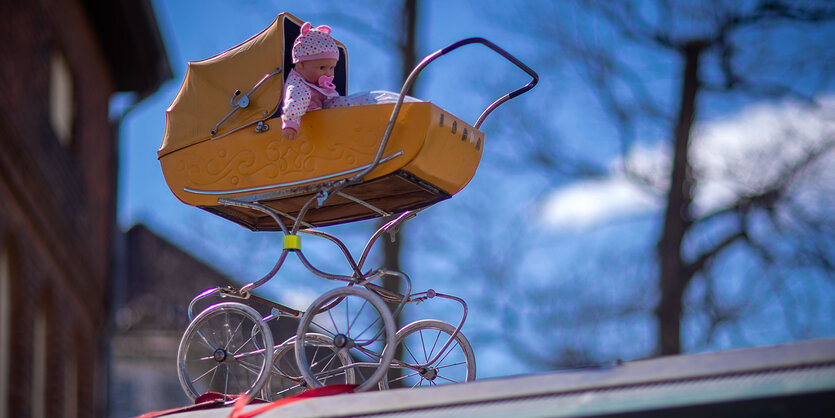 Ein gelber Kinderwagen mit einer Puppe darin