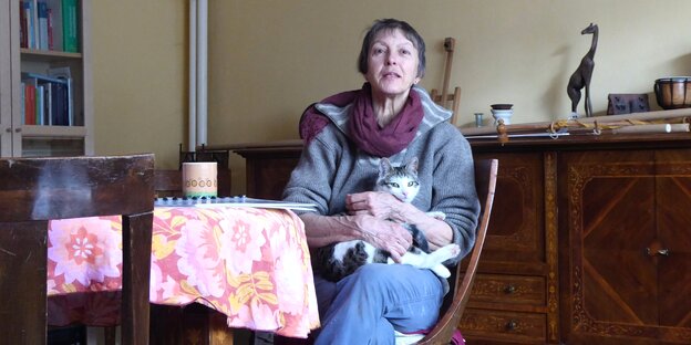 Giuliana Giorgi sitzt mit ihrer Katze auf dem Schoß am Tisch