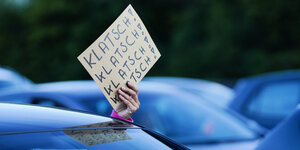 Eine Hand hält ein Schild aus dem Autofenster: Klatsch Klatsch Klatsch