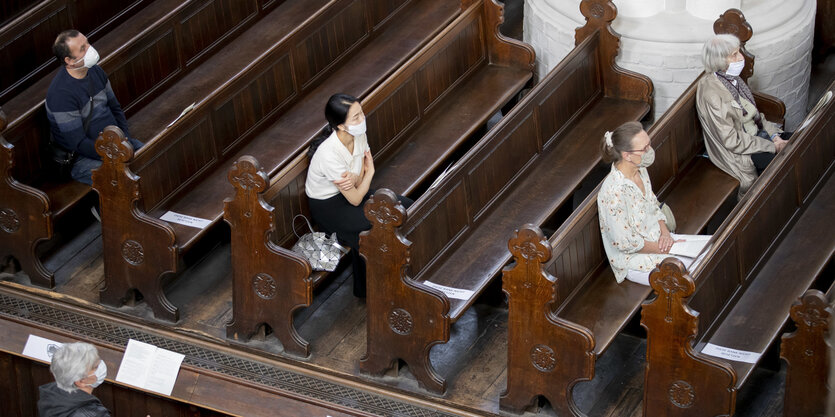 Wenige Menschen sitzen mit Abstand in der Kirche