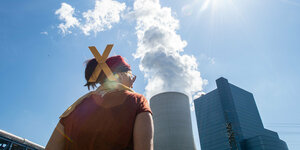 Eine Teilnehmerin steht beim Protest gegen das Kohlekraftwerk Dattel 4 mit einem X in den hochgesteckten Haaren vor dem Kraftwerk.