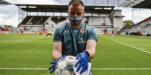 Schiedsrichter desinfisziert Spielball