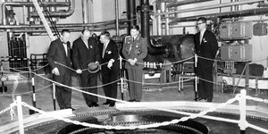 Ein altes schwarz-weiß Foto, auf dem Alte Männer um einen Reaktor stehen