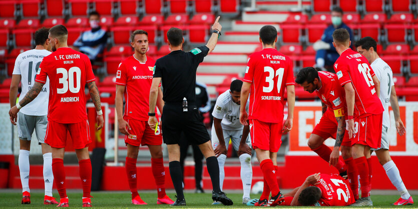 Union Berlin gegen Bayern München: Grischa Prömel liegt verletzt am Boden während Schiedsrichter Bastian Dankert mit einem Spieler spricht