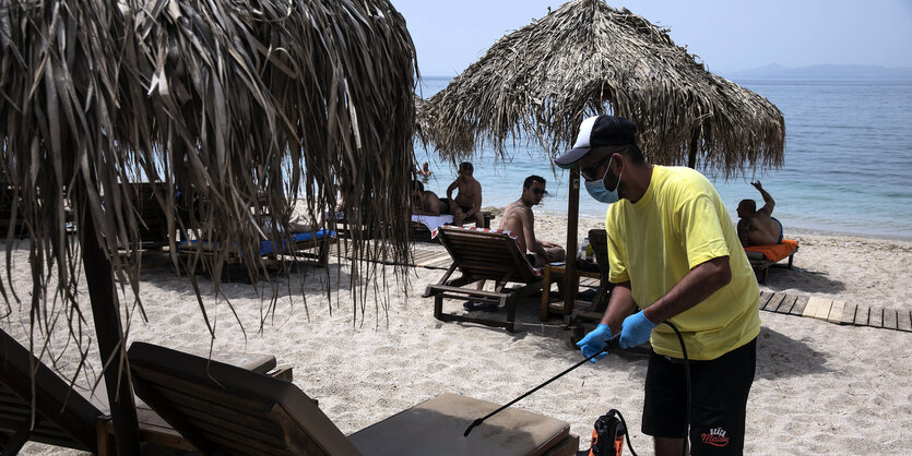 ein Mann desinfiziert Liegen am Strand