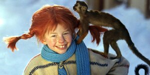 Ein Mädchen mit abstehenden roten Zöpfen und einem Affen auf der Schulter.